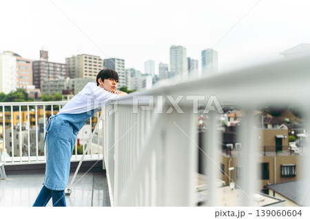 屋上で街を見つめる若い男性 139060604