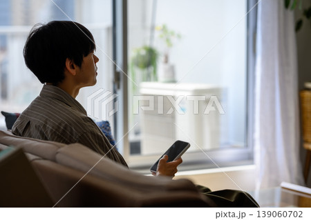 窓の外を眺めるスマホを持つ男性 窓の外を眺めるスマホを持つ男性 139060702