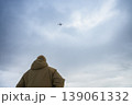 Rear view of soldier watching drone flying in cloudy sky 139061332