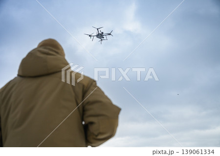 Rear view of soldier watching drone flying in cloudy sky 139061334