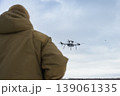 Rear view of soldier watching drone flying in cloudy sky 139061335