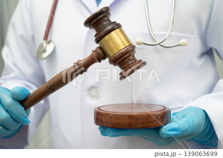 Asian doctor holding court hammer for and crime law justice, forensic medicine. Asian doctor holding court hammer for and crime law justice, forensic medicine. 139063699