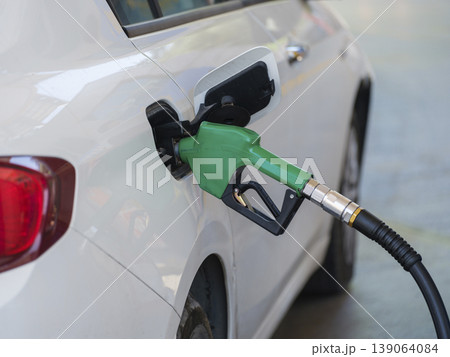 Gas pump nozzle in the fuel tank of a white car, refuel Gas pump nozzle in the fuel tank of a white car, refuel 139064084