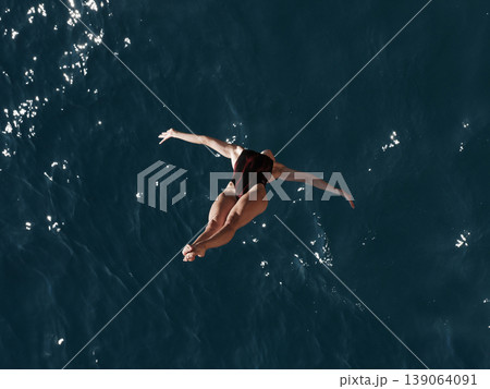 a professional female diver is jumping off a cliff into the sea a professional female diver is jumping off a cliff into the sea 139064091