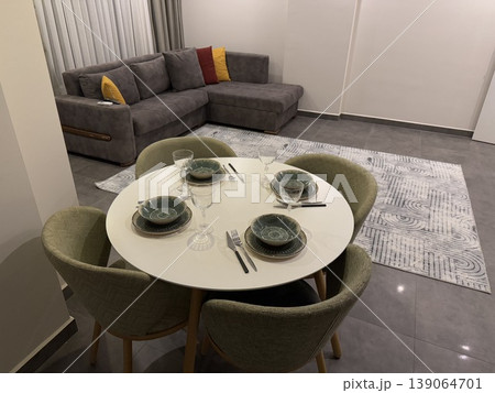 Modern dining area with set table and gray sofa background in a contemporary living room Modern dining area with set table and gray sofa background in a contemporary living room 139064701