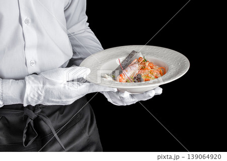 Waiter holding plate with grilled fish fillet and vegetables on black background 139064920