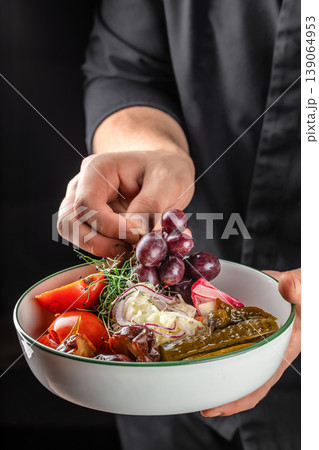 Hand holding bowl with pickled vegetables and grapes healthy food concept 139064953