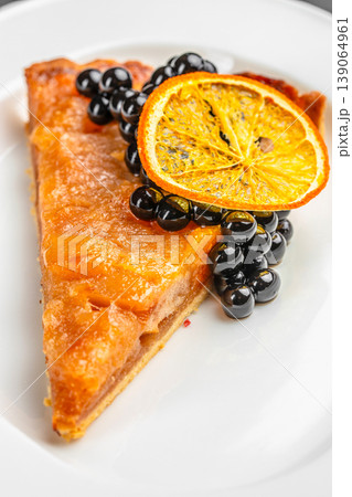Cake slice with black currant and dried orange close up on white plate dessert detail 139064961