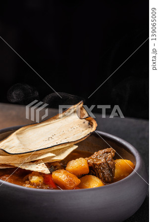 Meat stew with potatoes and bread in bowl dark background 139065009