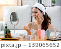 Beauty young asian woman applying cream on facial for wrinkles while looking mirror in living room. 139065652