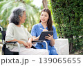 Female caregiver using digital tablet for senior patient consultation. 139065655