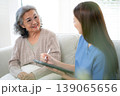 Asian woman caregiver using digital tablet for senior patient consultation. 139065656