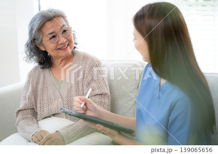 Asian woman caregiver using digital tablet for senior patient consultation. 139065656