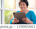 Senior asian woman relax on sofa reading tablet in living room at home. 139065661