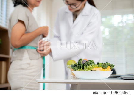 Nutritionist examining senior woman for weightloss planning for health in clinic office. 139065669