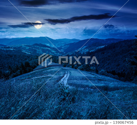 mysterious field on hillside in mountains near village at night. full moon over carpathian mountain landscape in summer. countryside view of alpine fields and rolling hills. cloudy sky 139067456