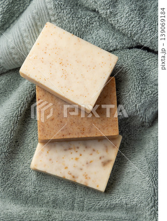 Brown and beige handmade solid soap bars on light green bath towel. Exfoliating scrub soap set 139069184