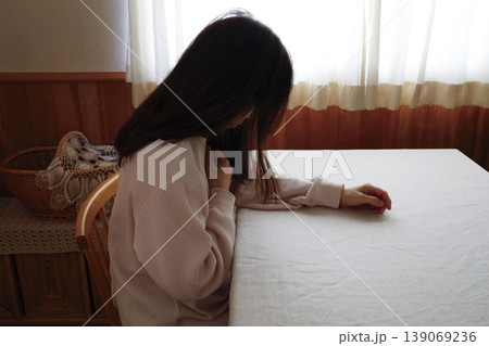 髪も整えず部屋着のまま力なくうつむく女性 139069236