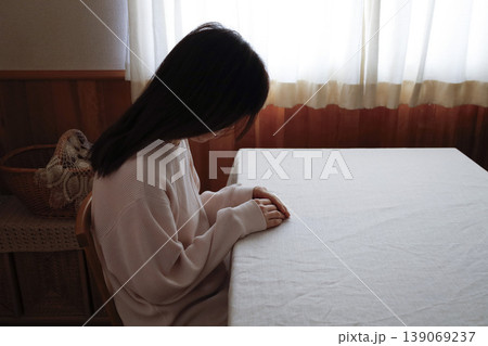 髪も整えず部屋着のまま力なくうつむく女性 139069237