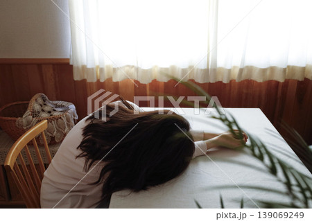 髪も整えず部屋着のまま力なく突っ伏す女性 髪も整えず部屋着のまま力なく突っ伏す女性 139069249