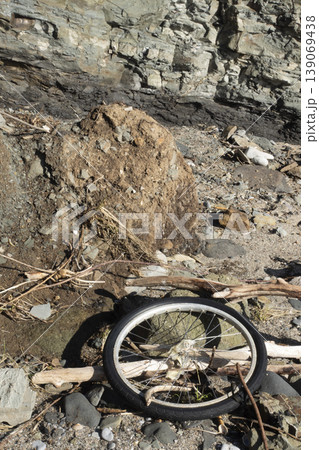 Rocky landscape with discarded bicycle wheel highlighting environmental pollution Rocky landscape with discarded bicycle wheel highlighting environmental pollution 139069438