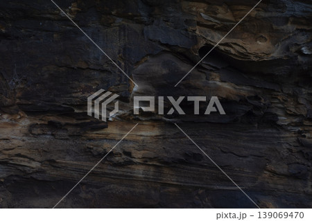 Dark natural layered rock formation with textured geological patterns 139069470