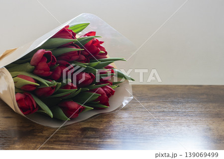 Bouquet of tulips in wrapping placed on table near window 139069499
