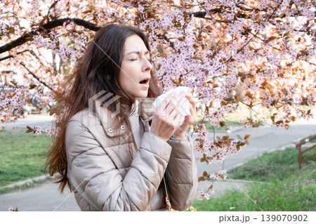 Side view of a woman sneezing into a tissue. Spring pollen allergy, hay fever sufferer, seasonal sickness. Side view of a woman sneezing into a tissue. Spring pollen allergy, hay fever sufferer, seasonal sickness. 139070902