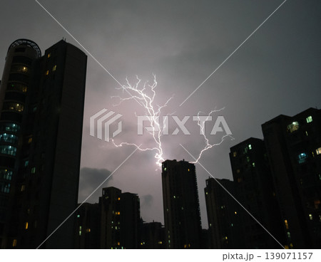 Powerful lightning bolt illuminates dark city buildings during a dramatic night storm Powerful lightning bolt illuminates dark city buildings during a dramatic night storm 139071157