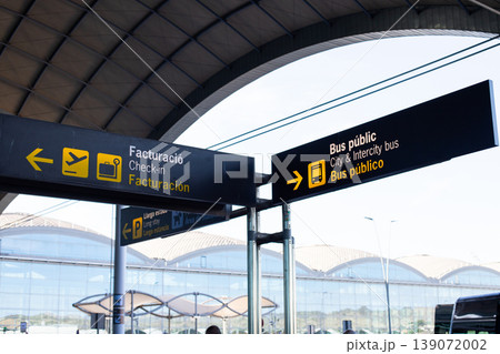 Airport signage indicating check-in and public bus services with clear directional arrows and modern architectural elements in the background 139072002