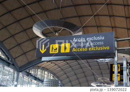 Sign indicating exclusive access with multilingual text and directional arrows inside a modern airport terminal Sign indicating exclusive access with multilingual text and directional arrows inside a modern airport terminal 139072022