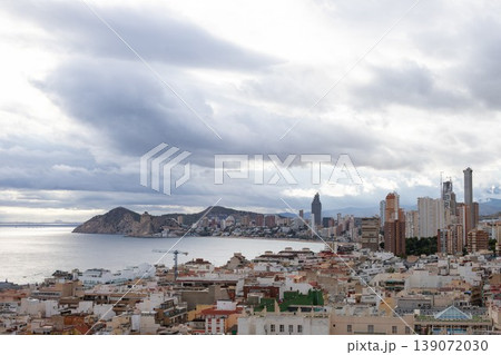 Coastal city skyline view with modern buildings, mountains, and cloudy sky over the Mediterranean Sea in Alicante, Spain 139072030