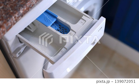 Washing machine detergent drawer with blue compartment for liquid detergent and white section for powder, positioned in a modern laundry room setting Washing machine detergent drawer with blue compartment for liquid detergent and white section for powder, positioned in a modern laundry room setting 139072051
