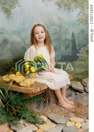 Cute child girl holding yellow tulips with ducklings, spring nature portrait with soft green background Cute child girl holding yellow tulips with ducklings, spring nature portrait with soft green background 139072604