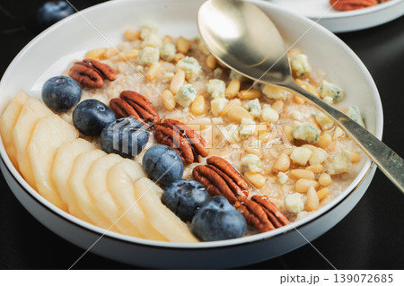 Oatmeal. Bowl of oatmeal porridge with blackberry, bananas and chia seeds on gray concrete old table background. Top view in flat lay style. Natural ingredients. Hot healthy breakfast and diet food Oatmeal. Bowl of oatmeal porridge with blackberry, bananas and chia seeds on gray concrete old table background. Top view in flat lay style. Natural ingredients. Hot healthy breakfast and diet food 139072685