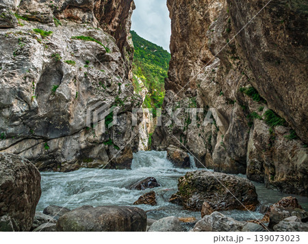 Rushing river powers through a dramatic rocky gorge, surrounded by towering cliffs 139073023