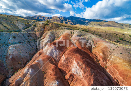Aerial view shows an exploration of Altai Mars landscape showing colorful hills and dramatic clouds during daytime under bright sunlight 139073078