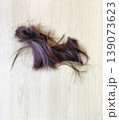 Strands of dark purple hair on light wood background 139073623