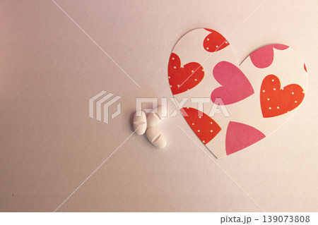 Heart-shaped figure with print with white capsules in light background. Heart-shaped figure with print with white capsules in light background. 139073808