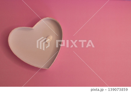 Heart-shape plate with white capsule on pink background Heart-shape plate with white capsule on pink background 139073859