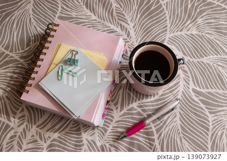 Office desktop top view showcasing a well-arranged work area with a coffee mug, notebooks and writing tools. Ideal for a productive freelance or student environment 139073927