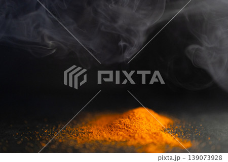 Side view of pile of red parika with smoke around it. Dark background Side view of pile of red parika with smoke around it. Dark background 139073928