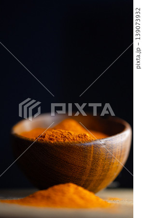 Vertical close up view of red paprika powder on a wooden bowl Vertical close up view of red paprika powder on a wooden bowl 139073932