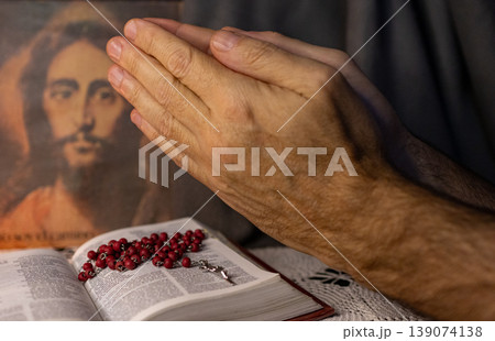 A man praying to the image of Christ. Bible and Rosary on his table 139074138