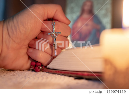 Woman holding a crucifix in her hand, praying 139074139