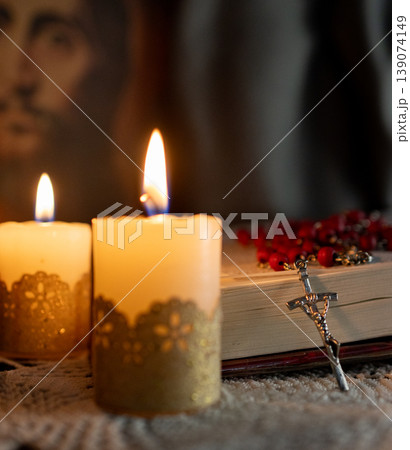 Catholicism culture .Candles lit on an altar. Image of Jesus in the background. 139074149