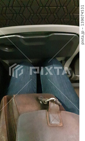 Legs cramped in small seat space on long-distance bus, mobile phone photo. Concept of travel, discomfort, transport, authenticity. Legs cramped in small seat space on long-distance bus, mobile phone photo. Concept of travel, discomfort, transport, authenticity. 139074531