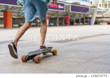 Senior traveler riding motorized longboard in city. Senior traveler riding motorized longboard in city. 139074775