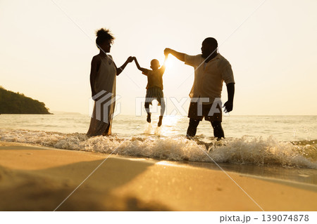 Silhouette of happy Black family jumping in the sea at sunset Silhouette of happy Black family jumping in the sea at sunset 139074878