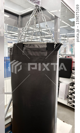 Heavy bag hanging on chains in a sports store during the day Heavy bag hanging on chains in a sports store during the day 139075169